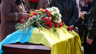 Cenaze vazosunda küller ve cenazede çiçekler. Çiçeklerle süslenmiş bir vazo ve cenaze töreninde yas tutan insanlar. Üzücü ve kederli bir şekilde ölen kişiye veda ediyorlar. n