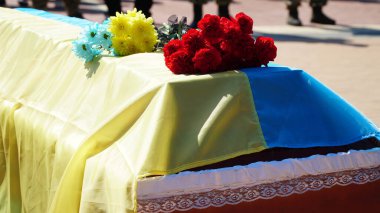 Cenaze vazosunda küller ve cenazede çiçekler. Çiçeklerle süslenmiş bir vazo ve cenaze töreninde yas tutan insanlar. Üzücü ve kederli bir şekilde ölen kişiye veda ediyorlar. n