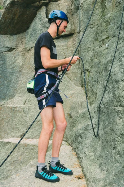 機器の若い男が石の岩の屋外の前に立って 登る準備をしています 屋外活動のためのトレーニングエリア 極端なスポーツ — ストック写真