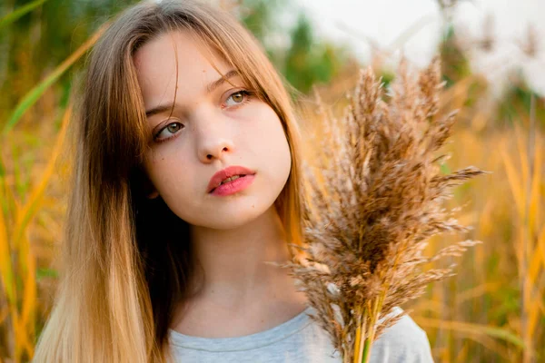 티셔츠와 청바지를 아리따운 소녀는 가을에 노란색 잔디에 기대고 아름다운 모델의 — 스톡 사진