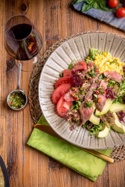 Kırmızı şarap ve sosla servis edilen yumuşak biftek salatası.