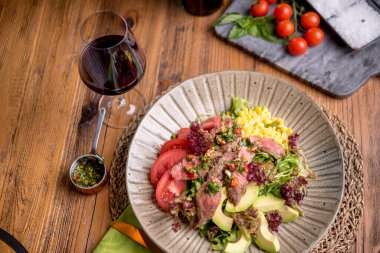 Kırmızı şarap ve sosla servis edilen yumuşak biftek salatası.