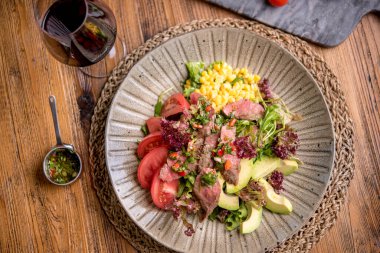 Kırmızı şarap ve sosla servis edilen yumuşak biftek salatası.