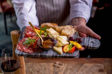 Önlüklü adam mermer tahtada çeşitli aperatifler servis ediyor.