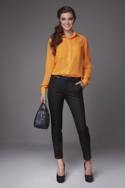 Beautiful sexy young business woman with evening makeup dressed in tight pants silk blouse with lace long sleeves high-heeled shoes and a small black handbag, business clothes for meetings and walks clipart
