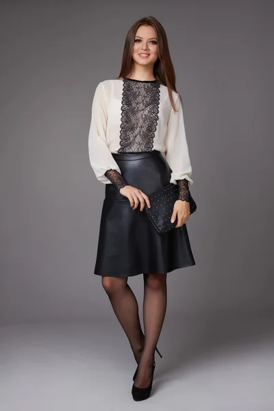 Mooie zakenvrouw met avond make-up dragen een rok aan de knie een zijde blouse met kant lange mouwen en schoenen met hoge hakken en een kleine zwarte handtas, zakelijke kleding voor vergaderingen en wandelingen — Stockfoto