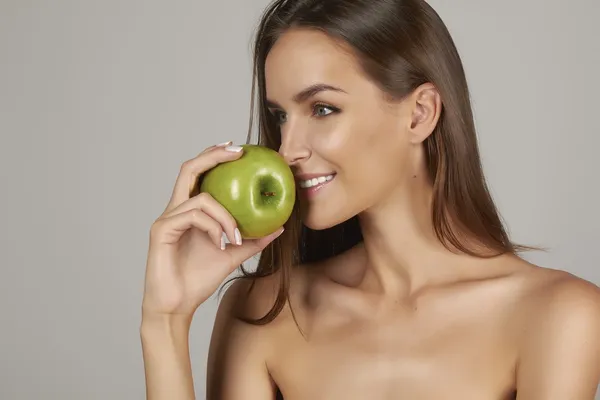 Young beautiful sexy girl with dark hair, bare shoulders and neck, holding big green apple to enjoy the taste and are dieting, healthy eating and organic foods, feeling temptation, hair shampoo — Stock Photo, Image