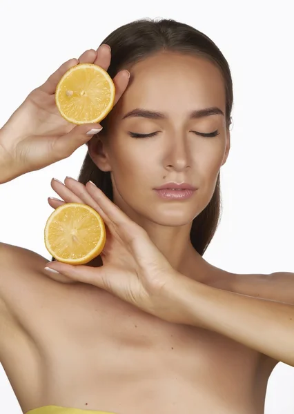 Mooie sexy jonge vrouw met perfecte gezonde huid en lang bruin haar dag make-up blote schouders houden oranje citroen grapefruit gezonde eten van biologisch voedsel dieet weight loss — Stockfoto