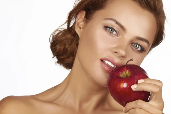 Молода красива сексуальна жінка з темним кучерявим волоссям, голими плечима і шиєю, тримає велике червоне яблуко, щоб насолоджуватися смаком і дієтою, здоровим харчуванням і органічними продуктами, відчуває спокусу, посмішку, зуби — стокове фото