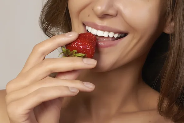 Mooi meisje met perfecte glimlach eten Rode aardbei. witte tanden — Stockfoto