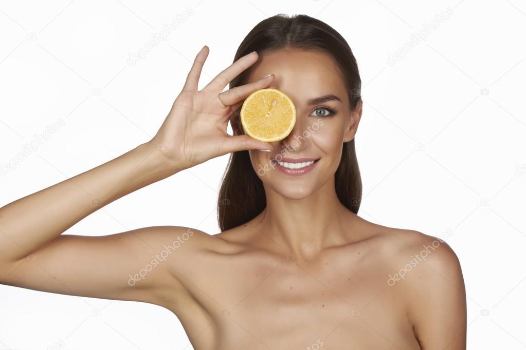 Beautiful sexy young woman with perfect healthy skin and long brown hair day makeup bare shoulders holding orange lemon grapefruit healthy eating organic food diet weight loss