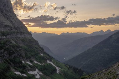 Buzul Ulusal Parkı 'ndaki Logan Geçidi' nden gelen yumuşak gün batımı ışığı dağların üzerinde parlıyor.