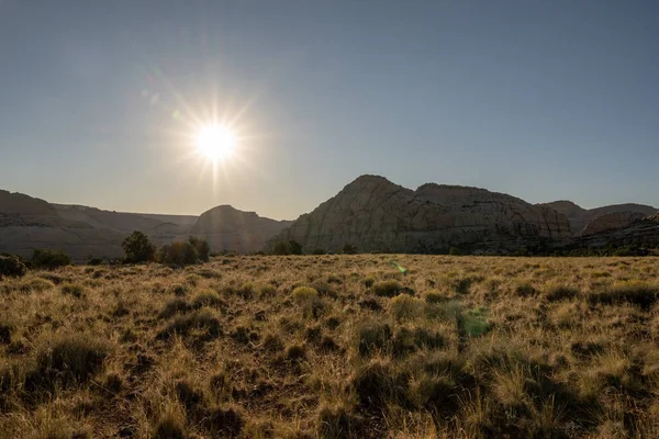 Sun Burst Over Field of Grass and Geological Features in Capitol Reef National Park