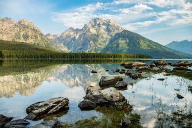 Grand Teton Ulusal Parkı 'nda sakin bir yaz sabahı Leigh Gölü' nde yansımalar