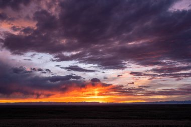 Orange and Purple Clouds Over Colorado Plains with mountains in the distance