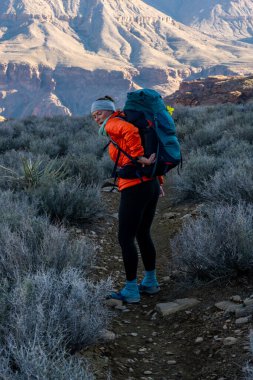 Female Hiker Struggling To Reach Something In Her Pack