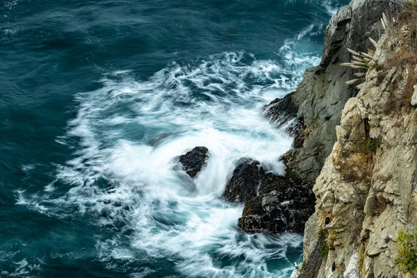 Waves Crash Below A Cliff In Big Sur along the California Coast