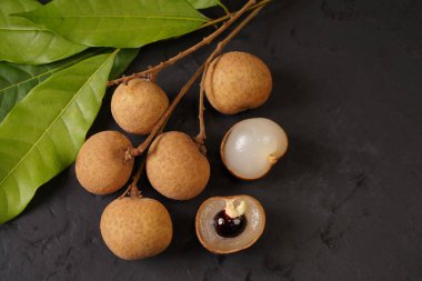 Siyah arka planda taze bir longan ve yaprak yığını. Tayland meyvesi.