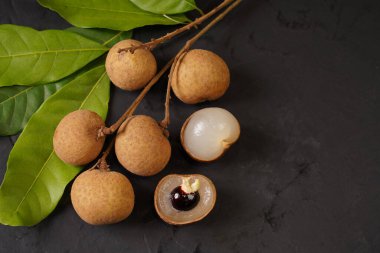 Siyah arka planda taze bir longan ve yaprak yığını. Tayland meyvesi.