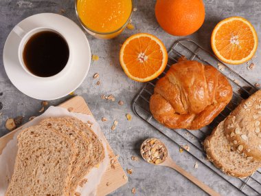 Siyah masa arkasına taze portakal suyu, ekmek ve kruvasan konmuş kahvaltı..   