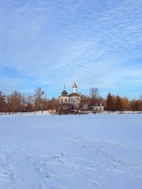 Kış manzarası, manzara. Karlı ovalar, uzaktaki ağaçlar ve bir kilise. Kış batımı. Noel zamanı ve yeni yıl. Karda ayak izleri.