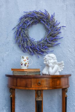 Çiçekleri, fincanı, kitapları ve porselen meleği olan antika büfe.