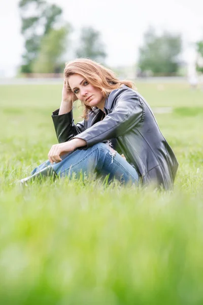 Young Brunette Woman Jeans Black Leather Coat Sitting Park — Zdjęcie stockowe