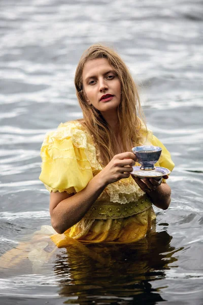Blond Kvinna Gul Historisk Klänning Stående Vattnet Håller Tekopp — Stockfoto