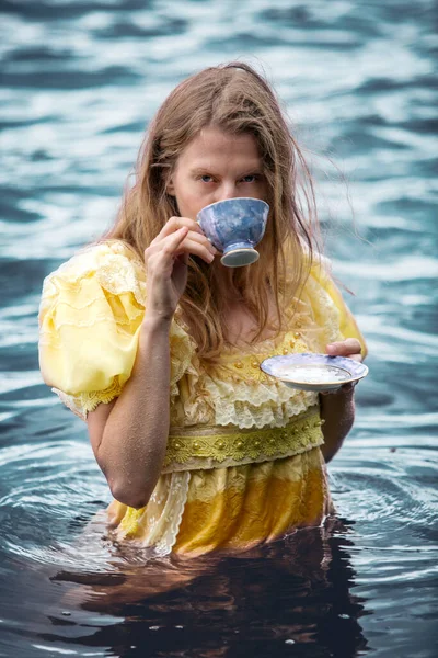 Mulher Loira Amarelo Vestido Histórico Água Segurando Uma Xícara Chá — Fotografia de Stock
