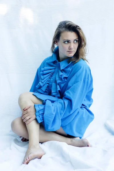 青いシャツを着た若い女性が白い毛布の上に座って — ストック写真