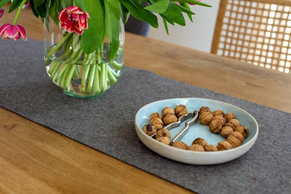 Skål Med Valnötter Och Vas Med Tulpaner Träbord — Stockfoto