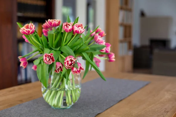 リビングルームのテーブルの上に赤いチューリップの花瓶 — ストック写真