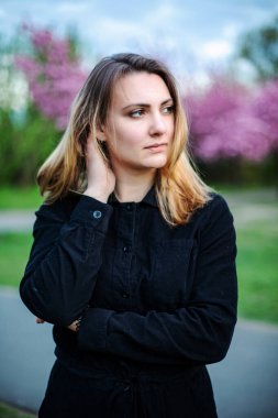 Parkta elinde kiraz çiçekleri olan esmer bir kadının portresi.