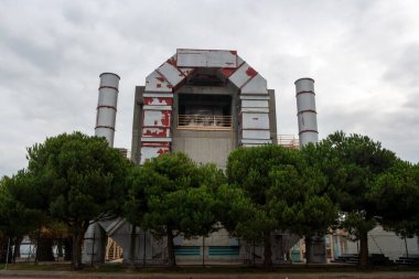 exterior view of a factory with chimney and palm tree