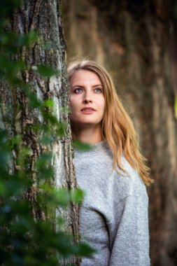 Ağaçların arasında duran sarışın kadın portresi