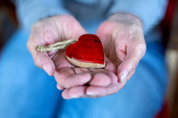 Close Older Womans Hand Holding Wooden Heart — Stock Photo, Image