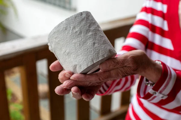 close-up of older woman holding a role toilet paper in her hands