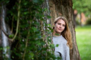 Ağaçların arasında duran sarışın kadın portresi