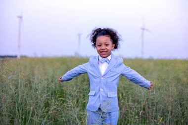 black boy in blue suit standing in a field and spreading his arms