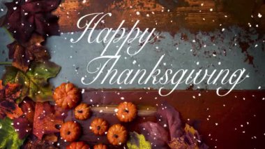 Cinemagraph of Happy Thanksgiving on wooden vintage board with pumpkins and leaves and snow