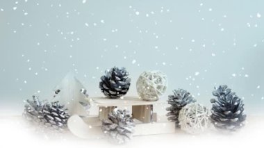Cinemagraph of miniature landscape with toy sleigh, pinecones and wooden tree with snowflakes