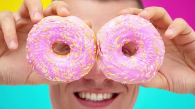 İki pembe donut tutan genç adamın sinema filmi. Gözlerinin önünde.