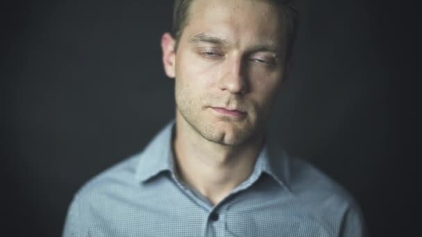 Close up of handsome man in shirt putting on glasses over black background — Stock Video