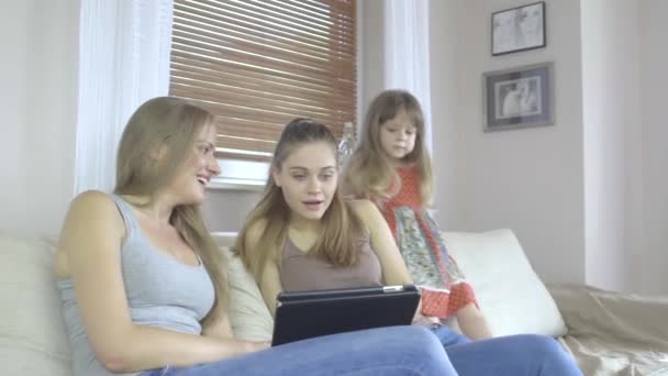 Two women and little girl sitting on couch with tablet computer. — Stock Video