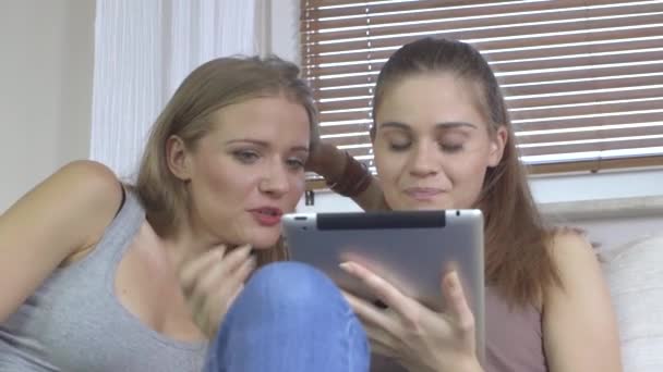 Duas mulheres bonitas olhando para baixo no computador tablet e falando — Vídeo de Stock