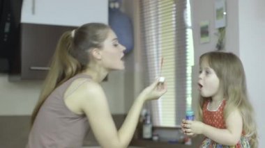 mutlu anne ve kızı mutfakta kabarcıklar üfleme.