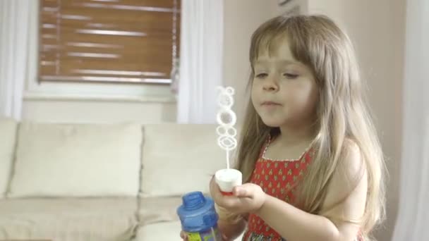 Menina bonito se divertindo e fazendo bolhas de sabão em casa — Vídeo de Stock