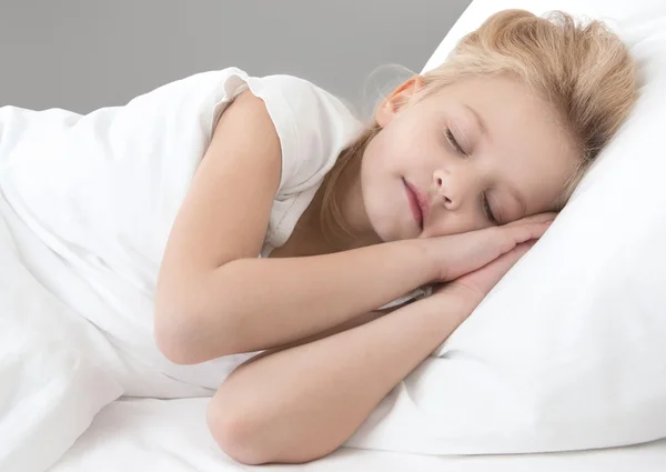 Søt, liten jente som sover på en hvit pute – stockfoto
