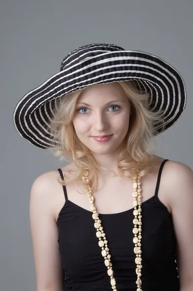 Jovem bela mulher loira sorridente em um chapéu e um vestido preto — Fotografia de Stock