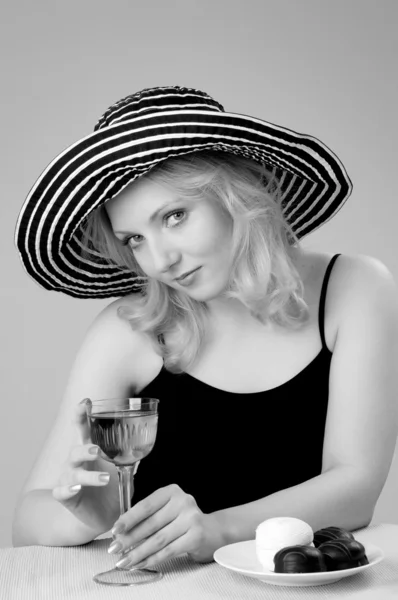年轻漂亮的金发女人，一杯红酒一顶帽子。 — 图库照片